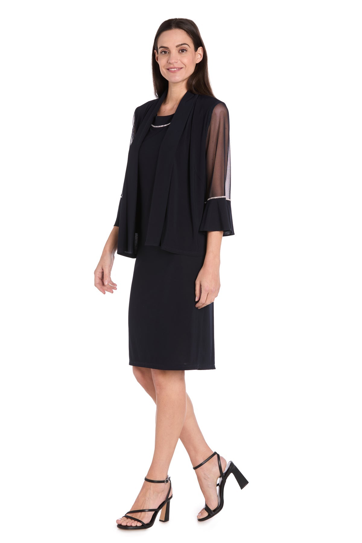 A woman models the R&M Richards 3747P Petite Two-Piece Party Dress—black chiffon with sheer sleeves and high-heeled sandals—against a white background, perfect for any special occasion.